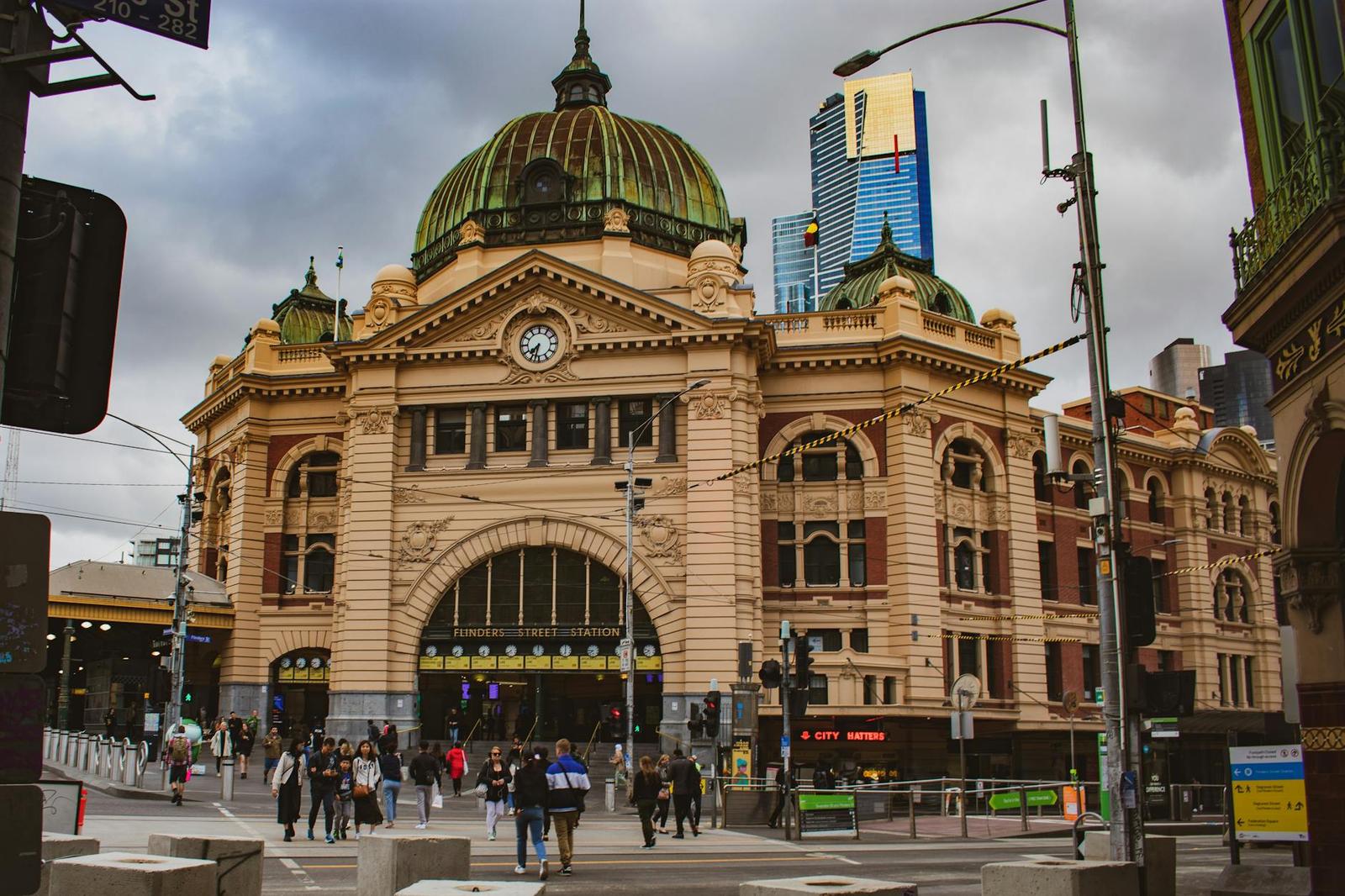 Pedestrians cross in front of an ornate domed railway station facade