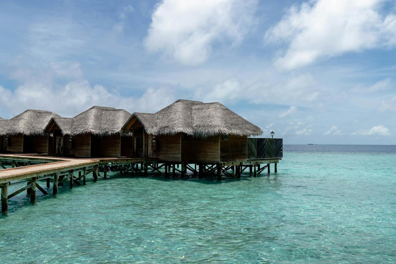 Thatched-roof overwater bungalows on stilts above a turquoise lagoon