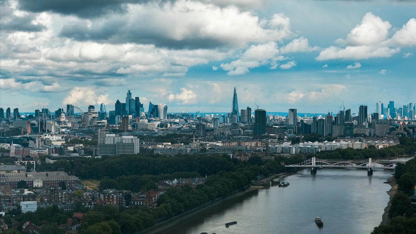 A wide river bend through a city with a tapering glass tower on the skyline
