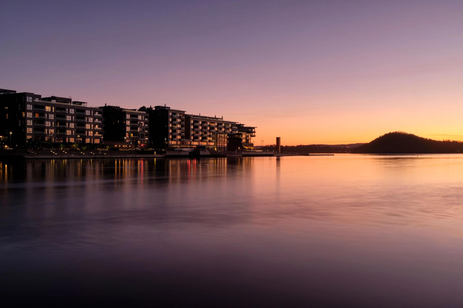 Captivating sunset view of Oslo's waterfront, reflecting colorful hues over calm waters
