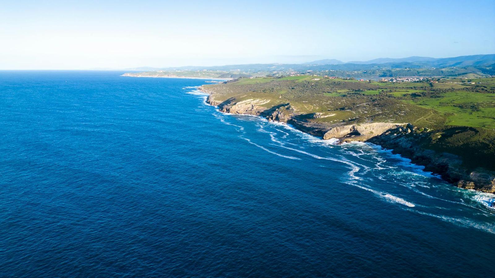Aerial view of a rugged coastline where cliffs meet a deep blue sea