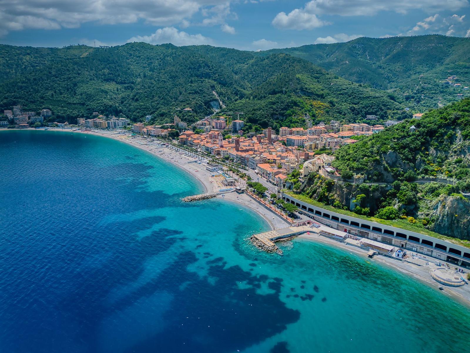 Aerial view of a seaside town curving around a turquoise bay