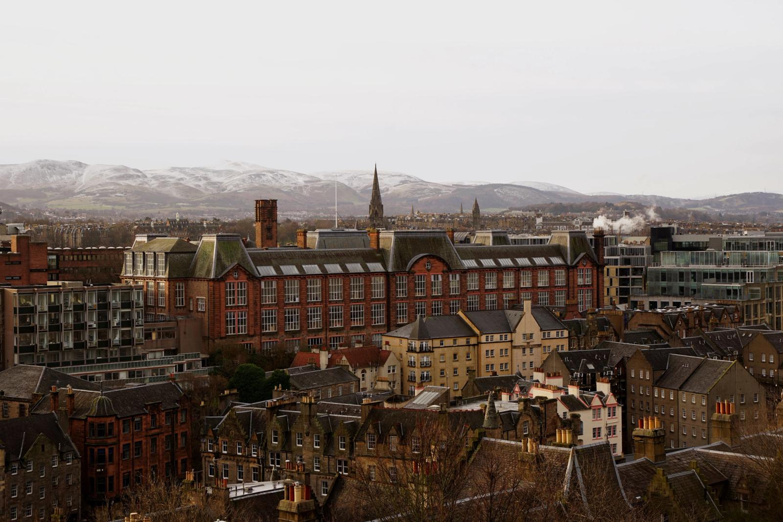A stunning Edinburgh cityscape showcasing historic architecture and distant snow-capped mountains