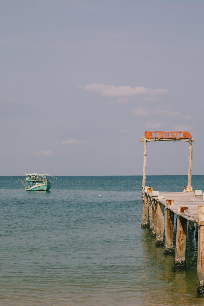 Weathered wooden pier extending toward a fishing boat at sea
