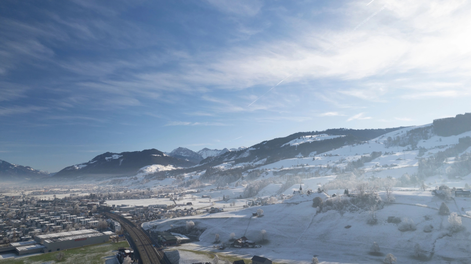 Aerial view of Altendorf, Schwyz, Switzerland with snow-covered mountains and blue sky