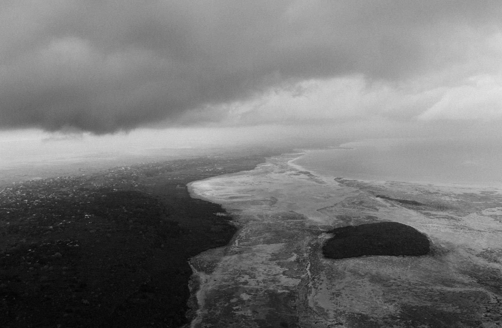 Black and white aerial of a stormy coastline under heavy clouds