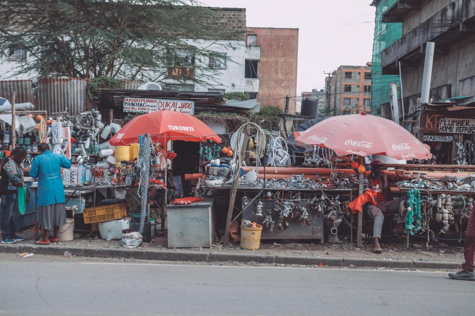Street vendors selling goods from stalls shaded by red umbrellas
