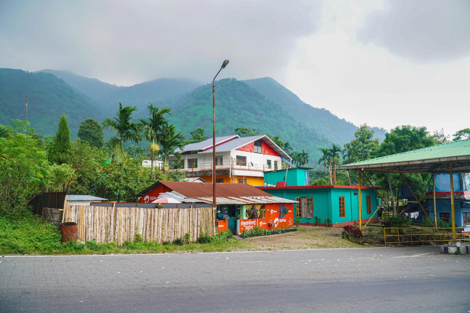A vibrant Indian village set against misty mountains and lush greenery, showcasing rural life