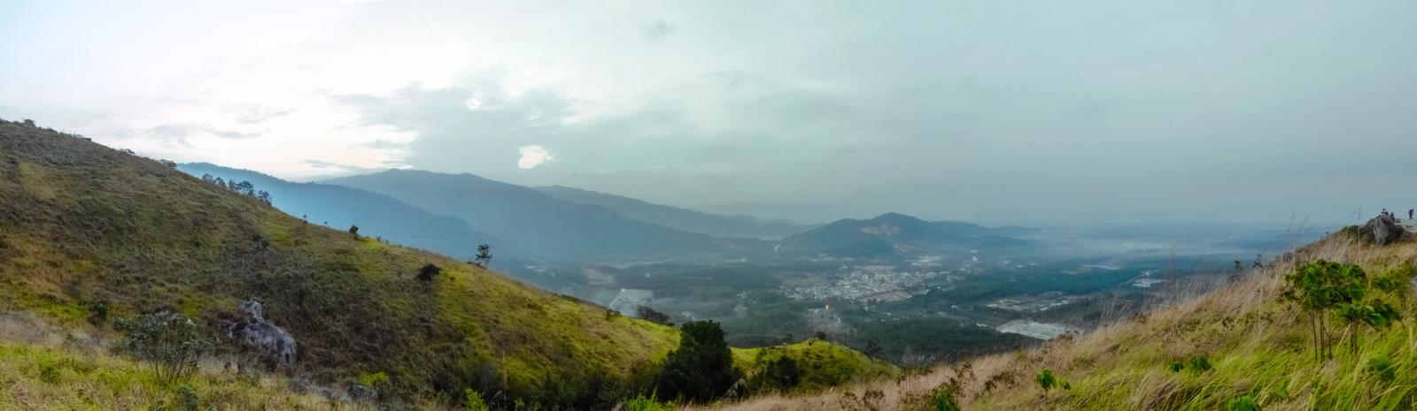 Breathtaking panoramic view from a hilltop overlooking a misty valley and distant town
