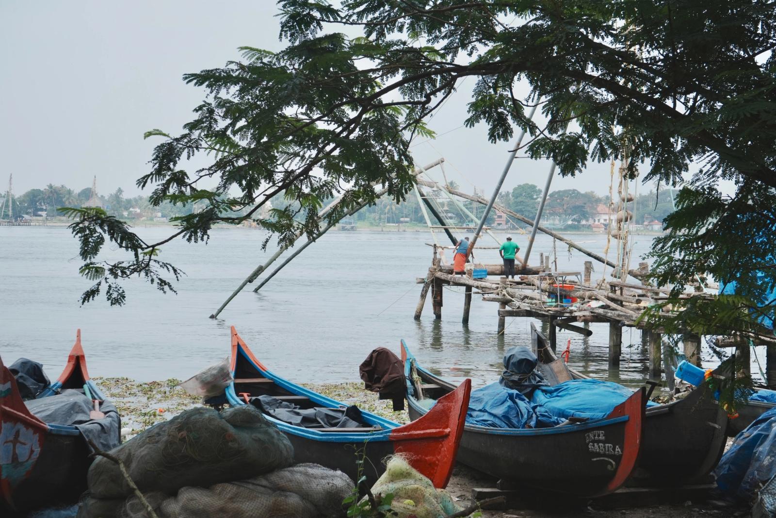 Traditional fishing boats and Chinese fishing nets by a river in India, capturing local culture