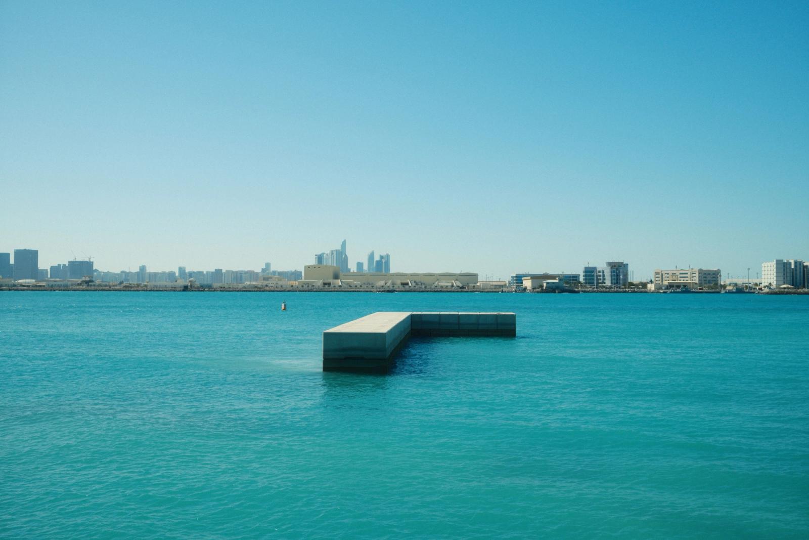 Vivid skyline of Abu Dhabi with clear blue waters under a bright sky, captured from the waterfront