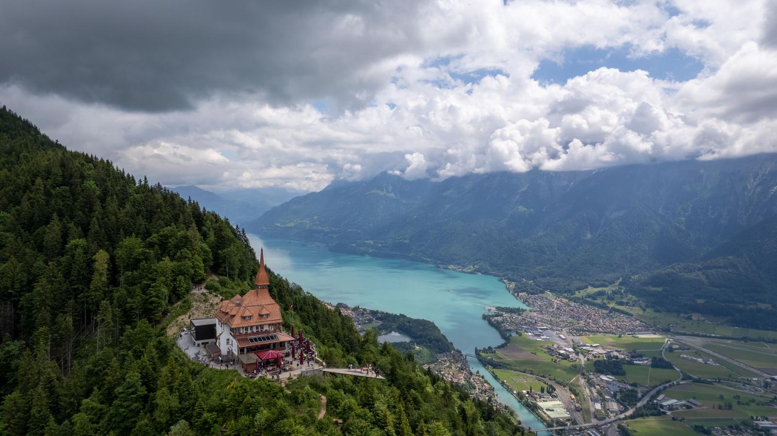 Aerial view of a forested ridge overlooking a wide turquoise valley lake