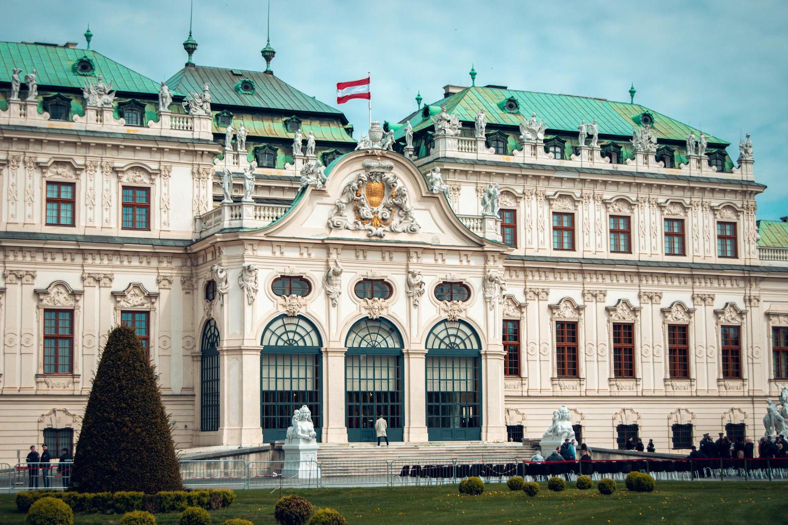 A cream baroque palace with green domed towers and manicured gardens in front