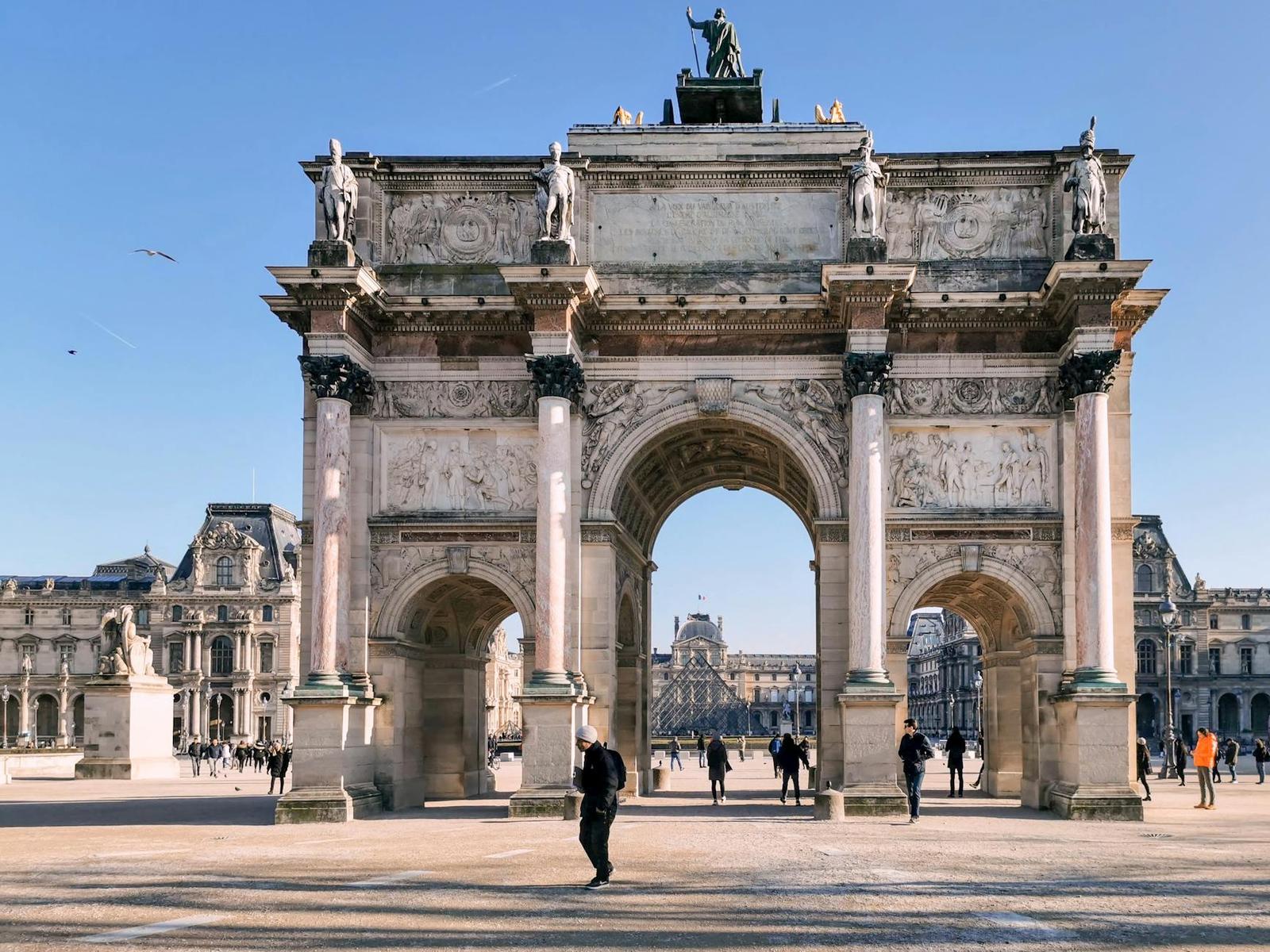 The iconic Arc de Triomphe du Carrousel at the Louvre in Paris, surrounded by tourists