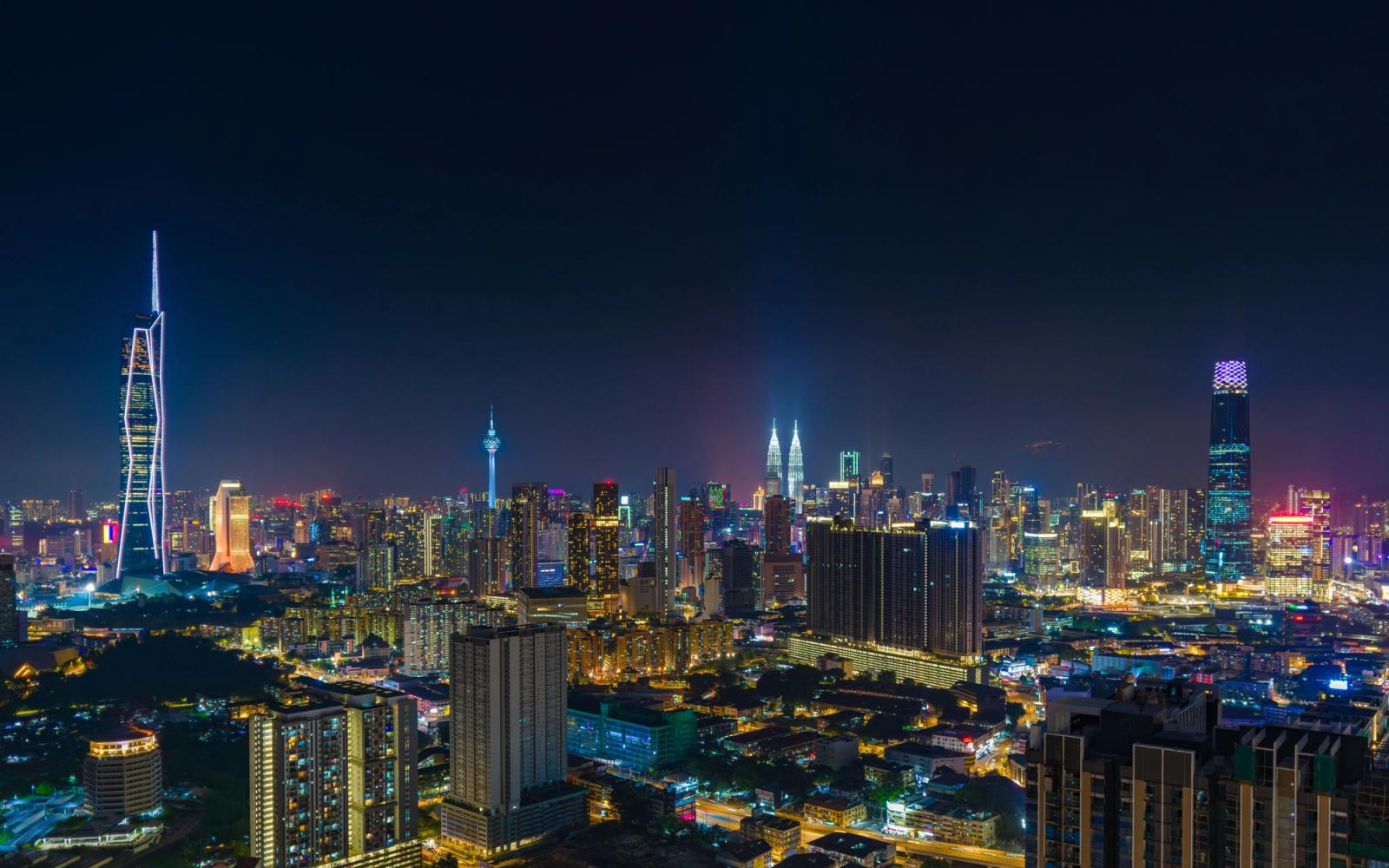 A vibrant night view of Kuala Lumpur's skyline featuring the iconic Petronas Towers
