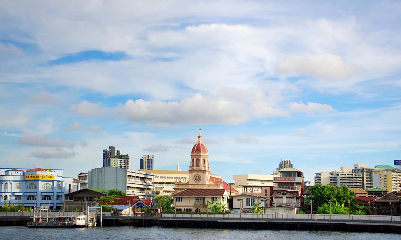 Charming riverside view in Bangkok showcasing iconic architecture under a vibrant sky