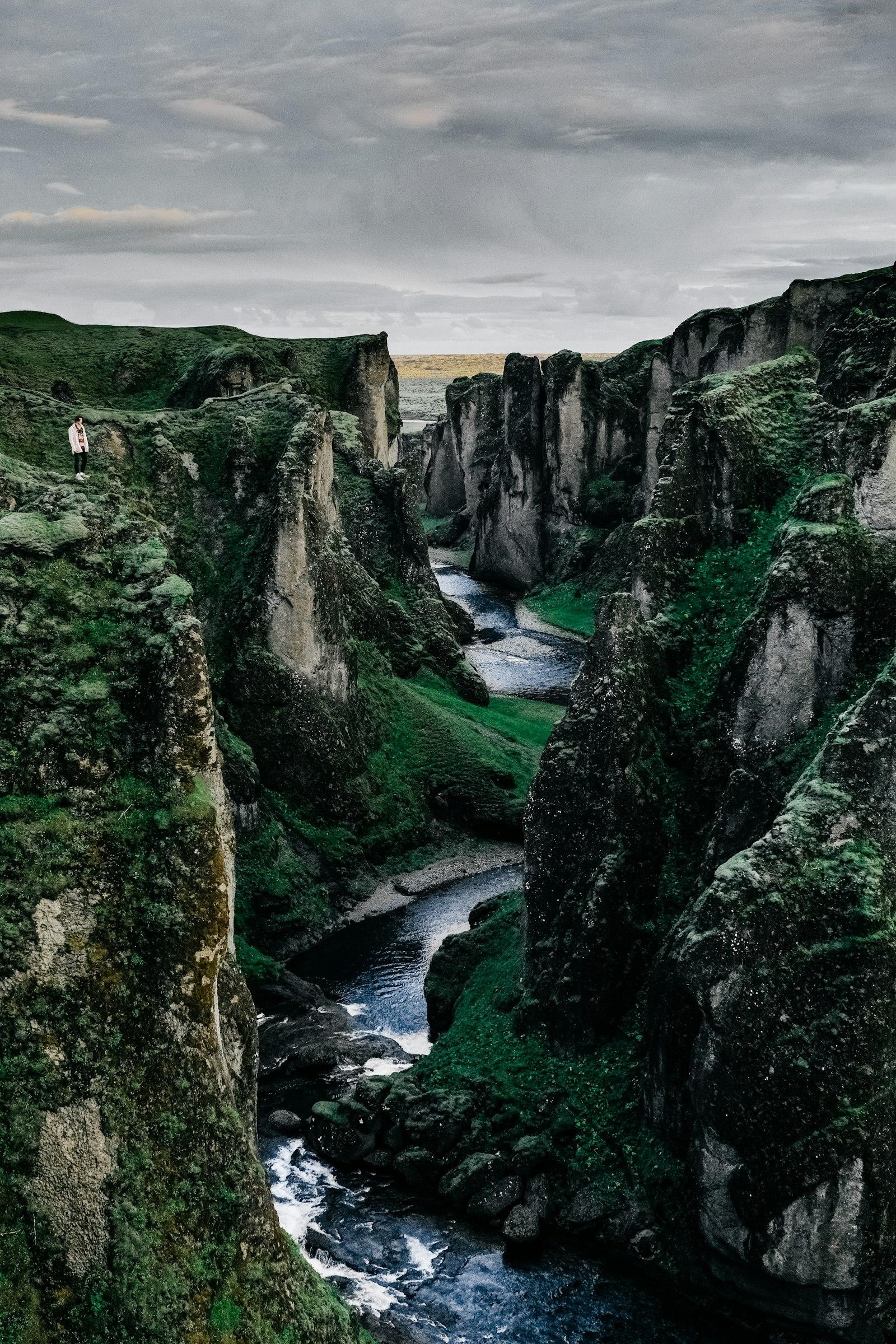 Green moss-lined Icelandic canyon under a dramatic sky