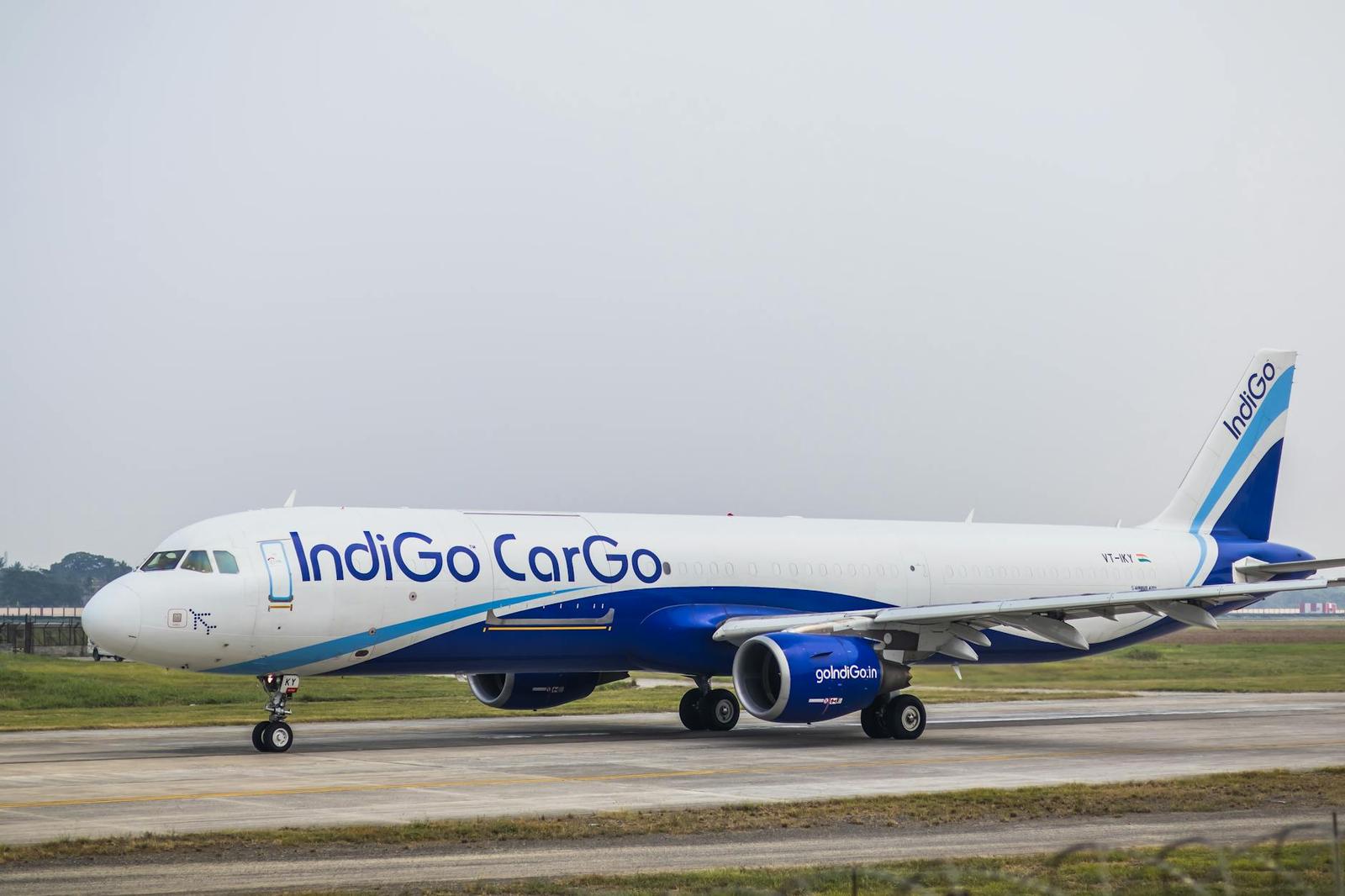 A blue and white cargo aircraft taxiing on an airport runway