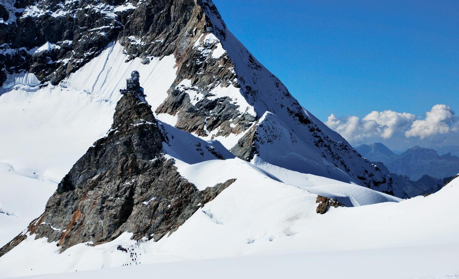 Rocky mountain summit with an observatory building amid snowfields