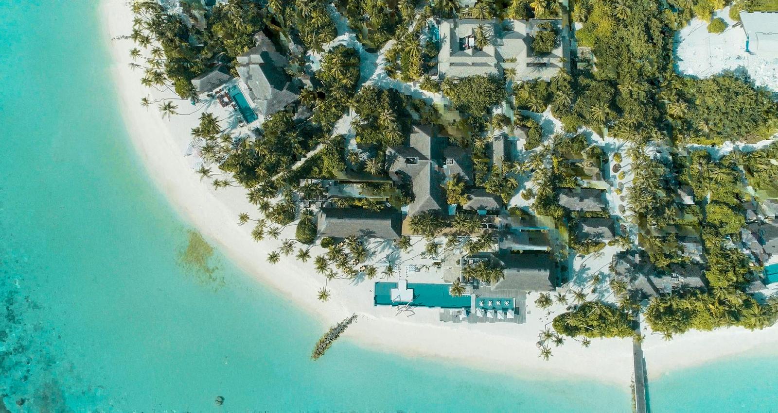 Aerial view of a resort with a pool nestled among palm trees