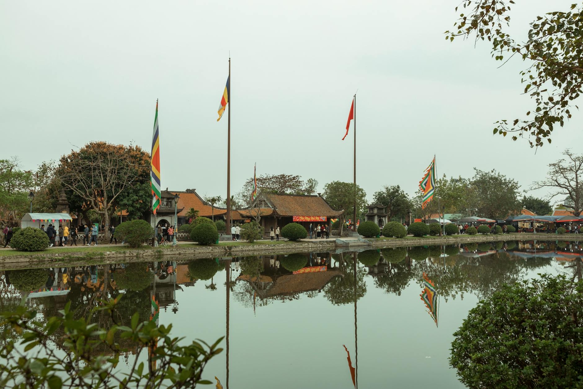Temple pavilion with colourful flags reflected in a still lakeside pond