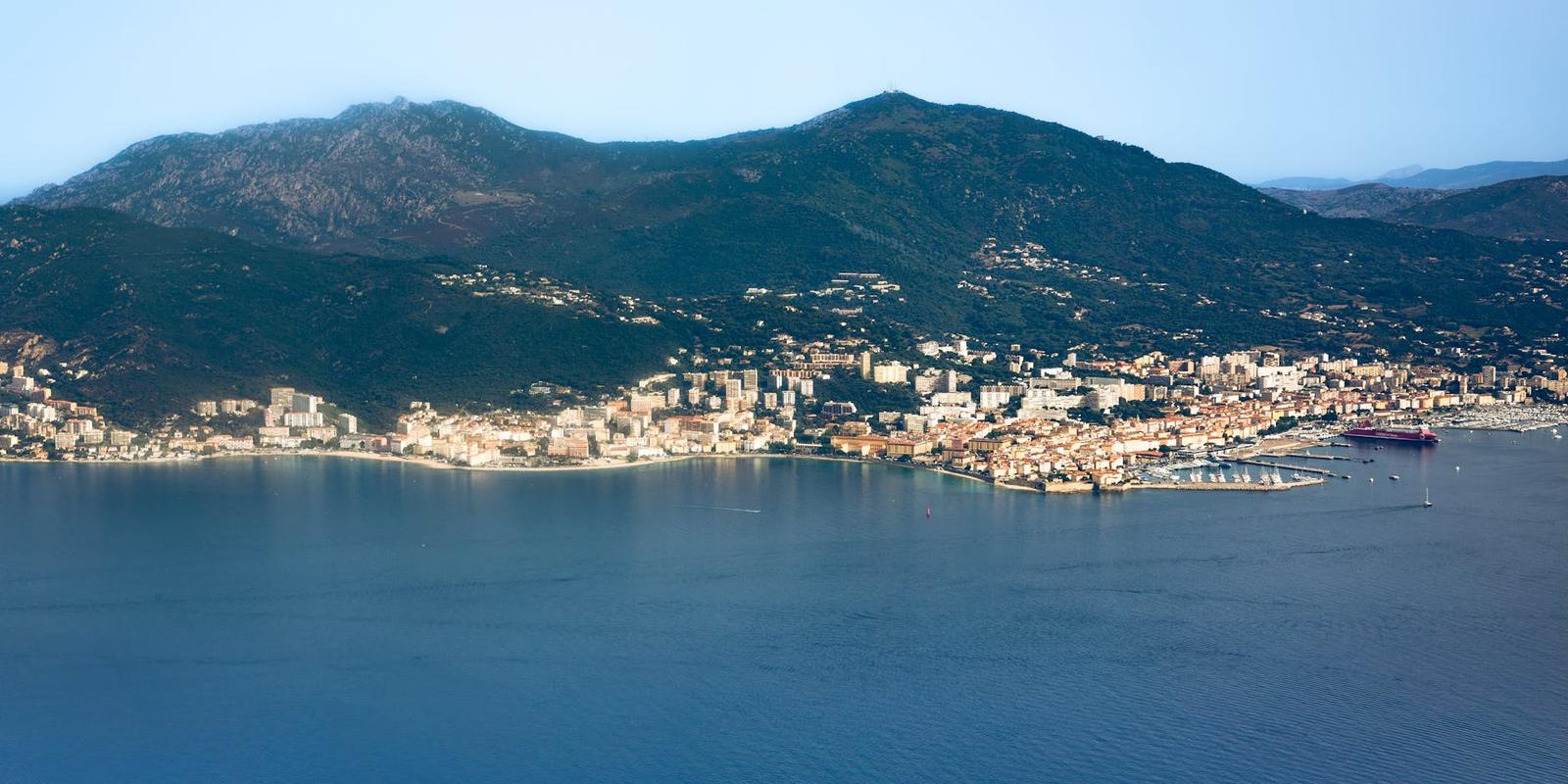 A coastal town nestled between green hills and a calm bay
