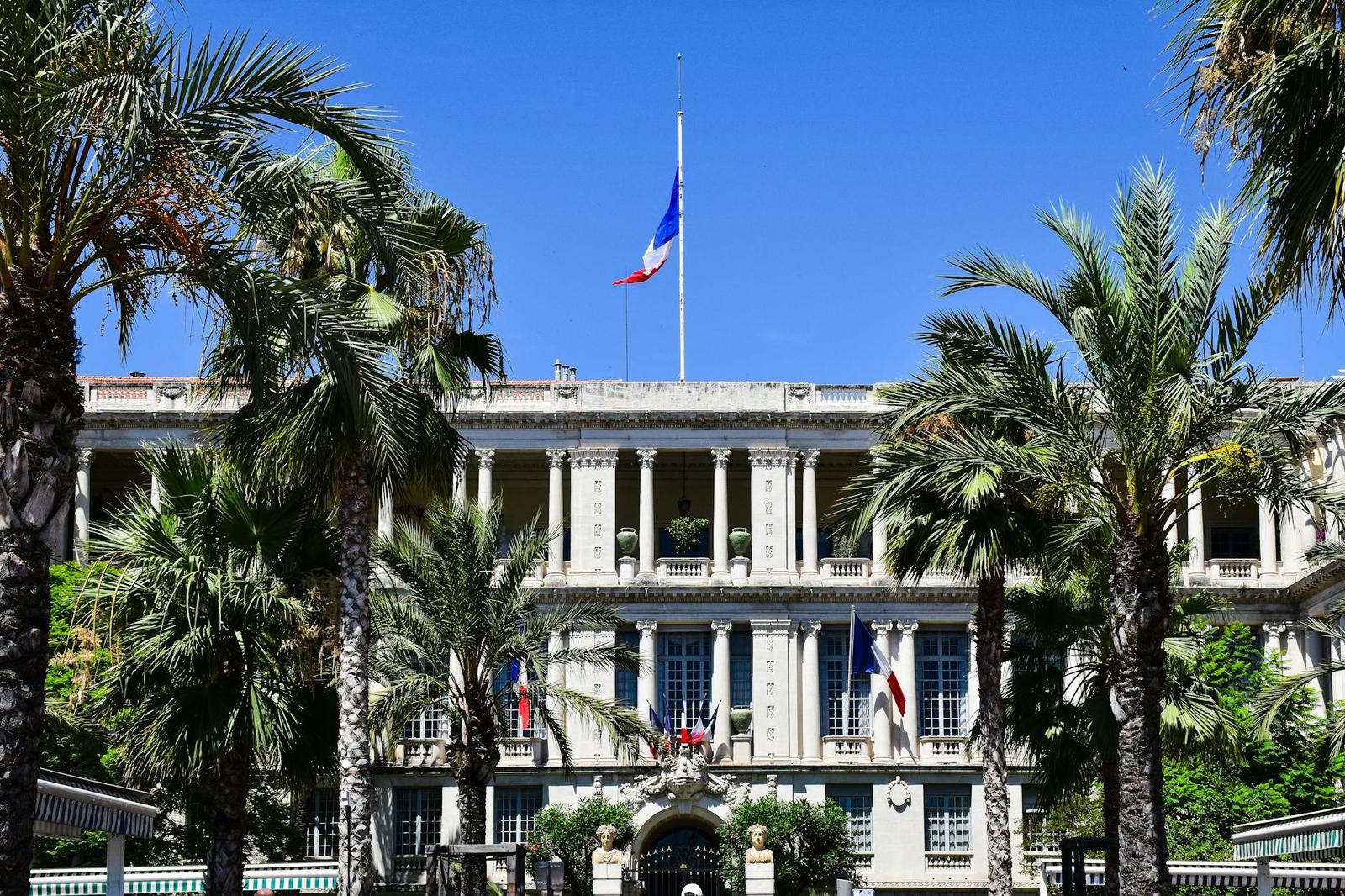 Elegant French colonial-style building surrounded by palm trees in Nice, France