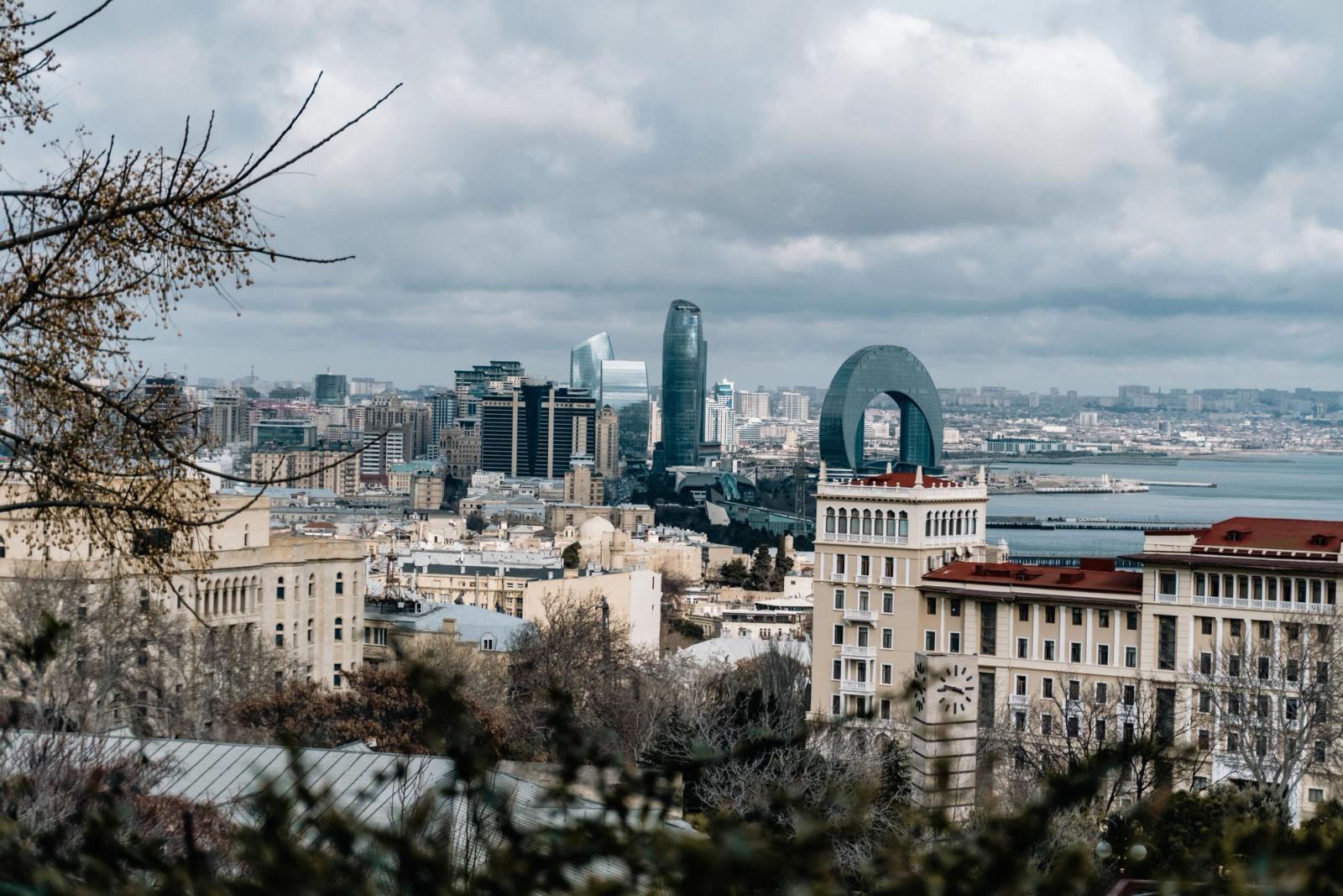 A scenic view of Baku's skyline featuring the Flame Towers under a cloudy sky