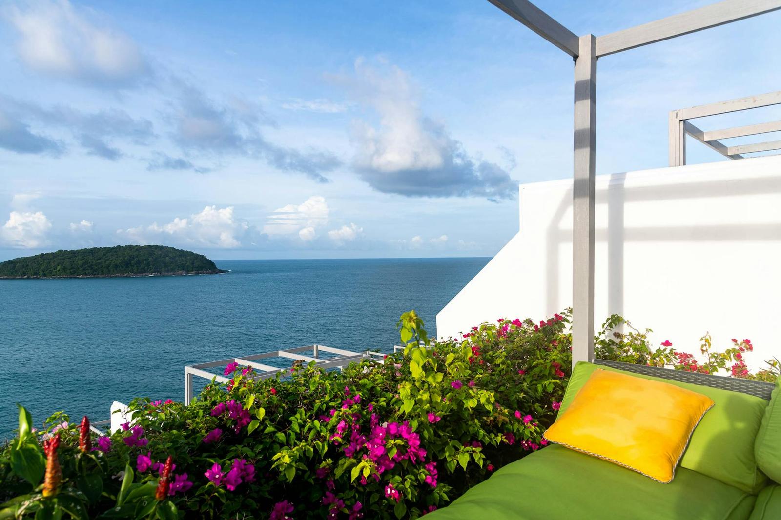 Rooftop lounge with a yellow cushion and bougainvillea overlooking the sea