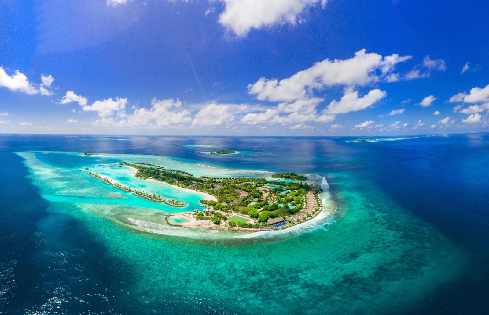 Aerial view of a resort island bordered by coral reef and open sea