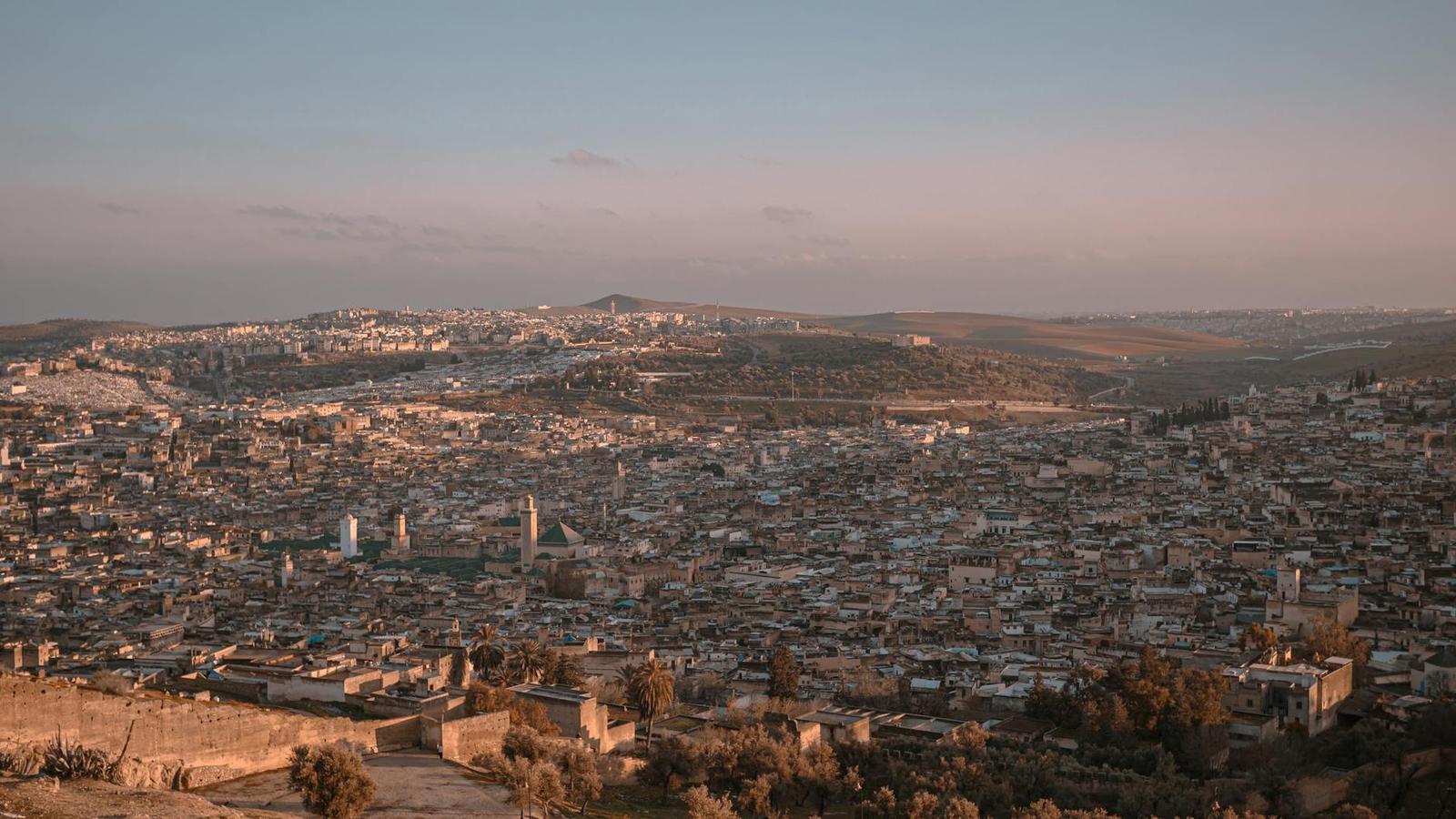 An aerial view of a dense old city spreading across hills at dusk