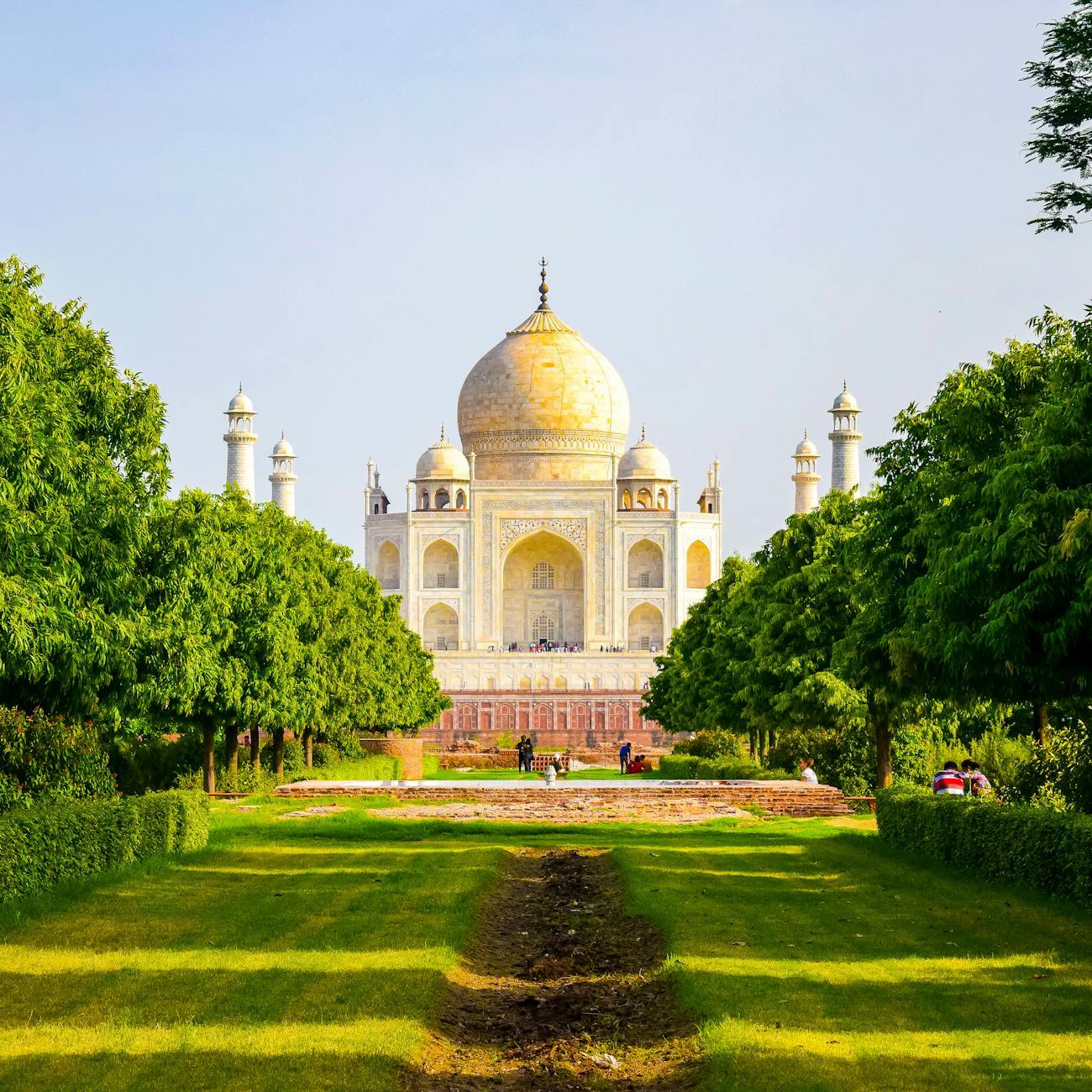 White marble domed mausoleum framed by a tree-lined garden path