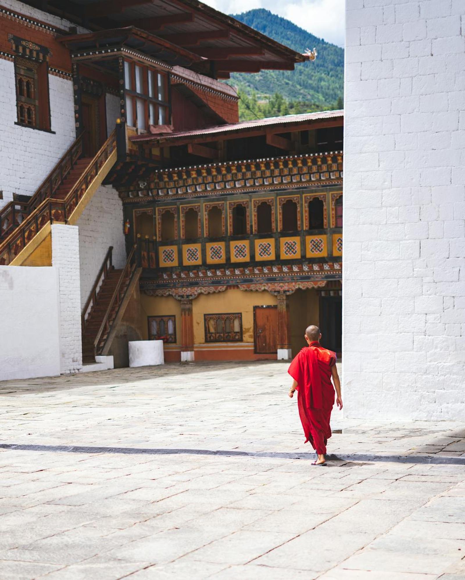 A monk walks through a traditional Bhutanese monastery courtyard in Thimphu