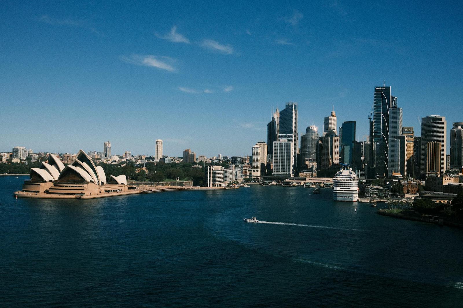 Sydney's harbour skyline with the Opera House beside a passing cruise ship