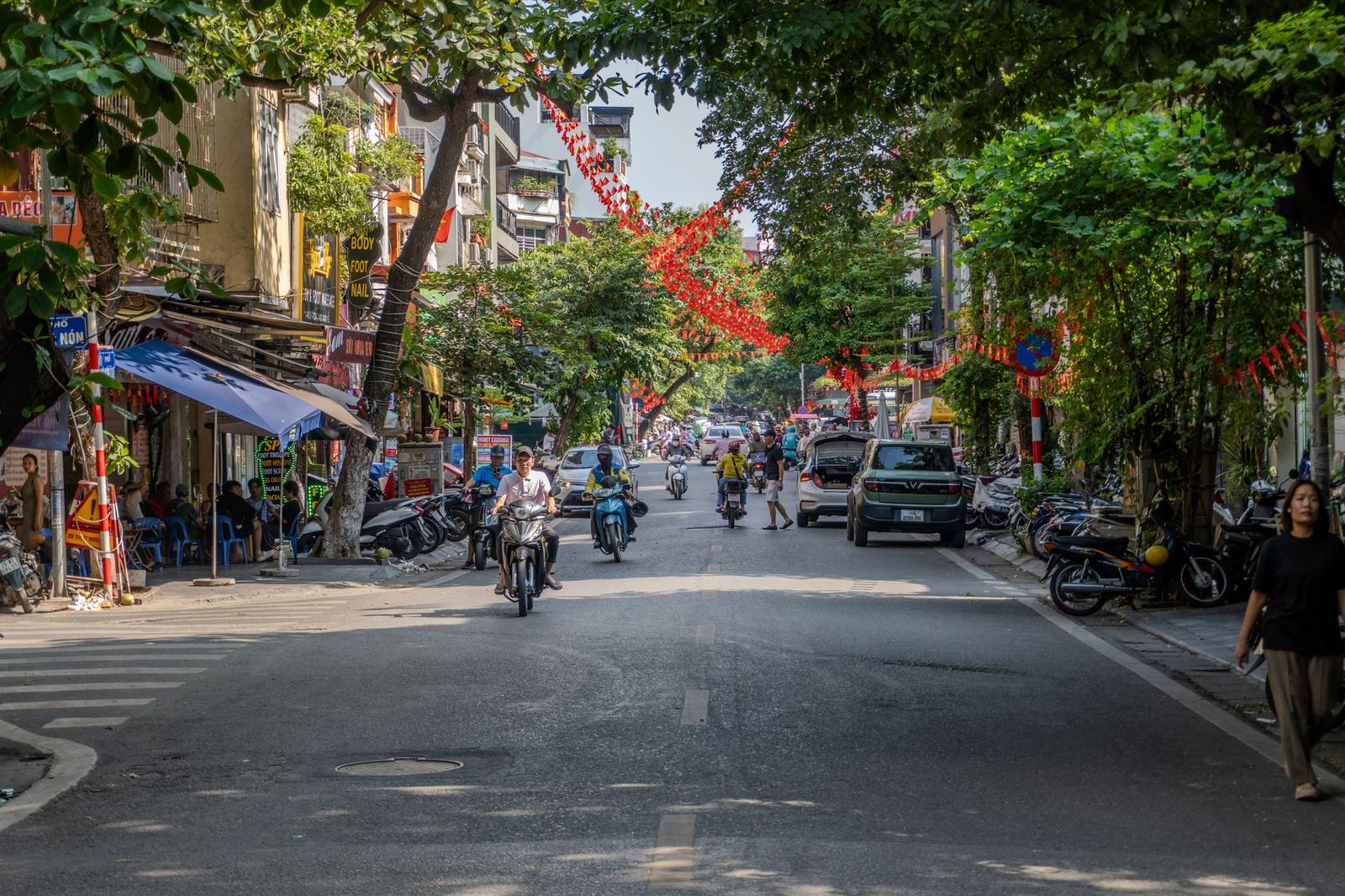 Old quarter street strung with red decorations and busy with motorbikes and pedestrians
