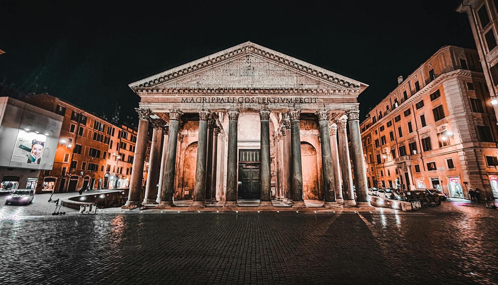 The Pantheon's columned portico illuminated at night in a Roman piazza