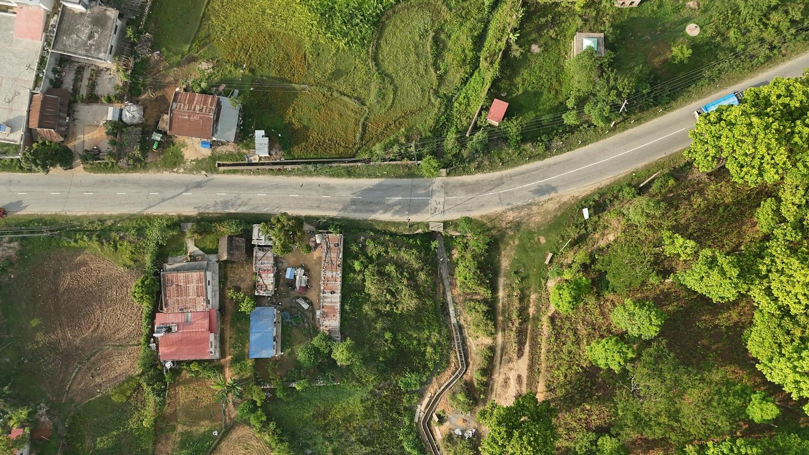 Aerial view of a road cutting through farmland and rooftops