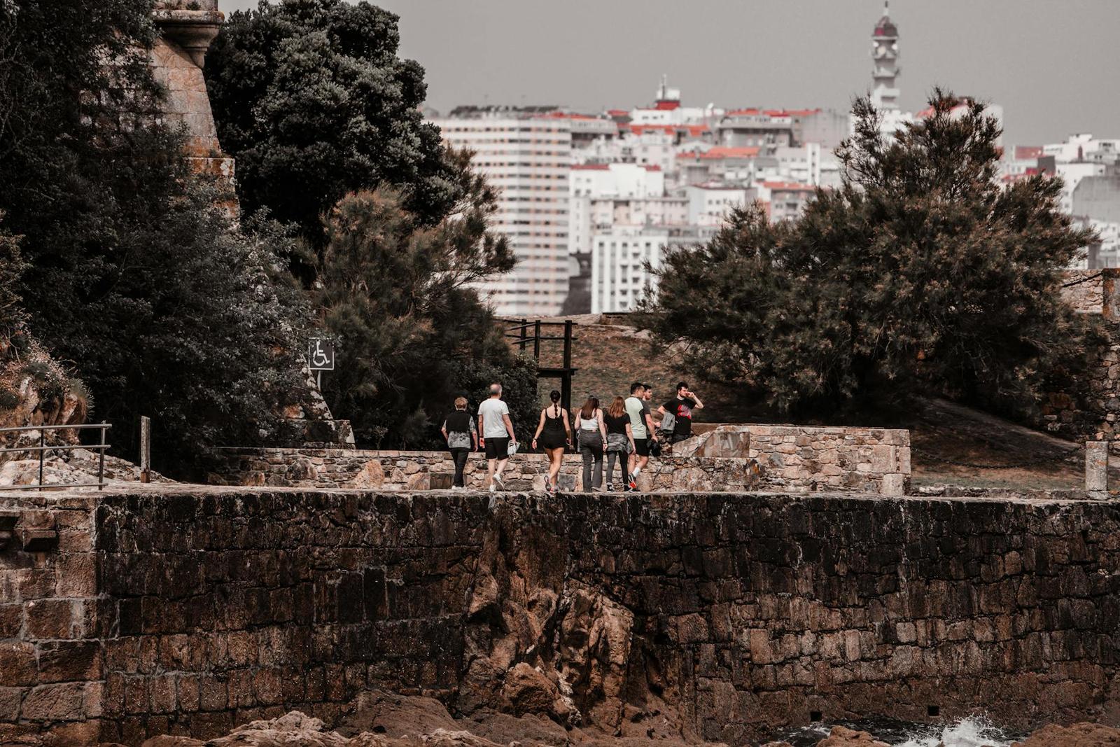 Tourists walking along the historic stone path at Porto de Santa Cruz with cityscape in background