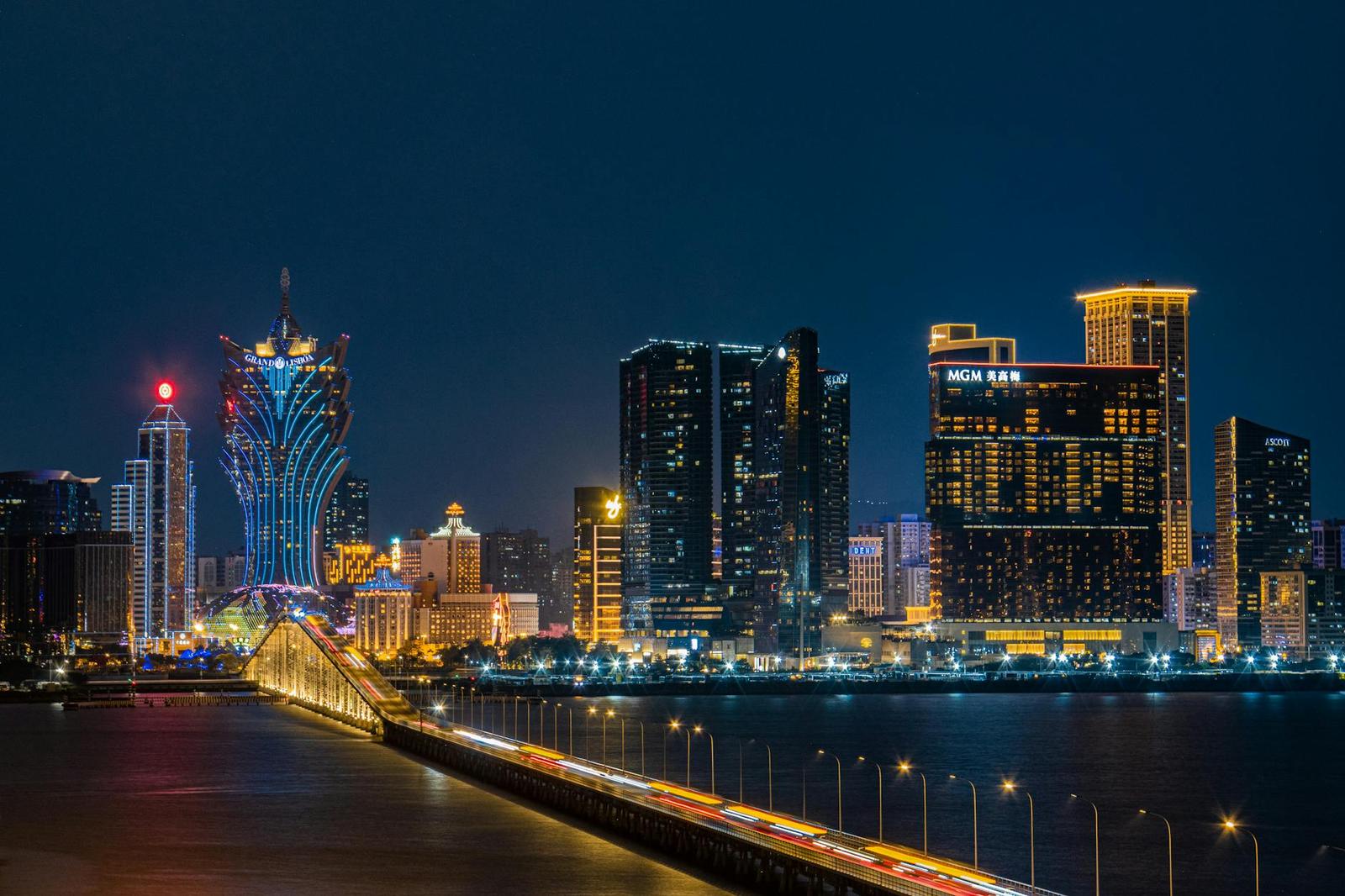A city skyline lit up at night beside a bridge crossing the water