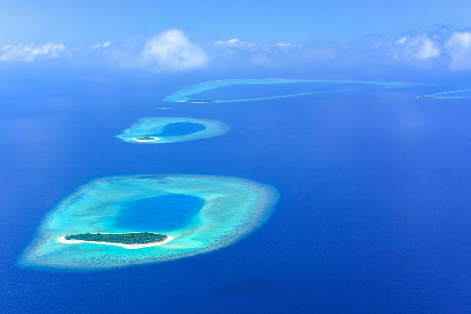 Aerial view of coral atolls scattered across a deep blue sea