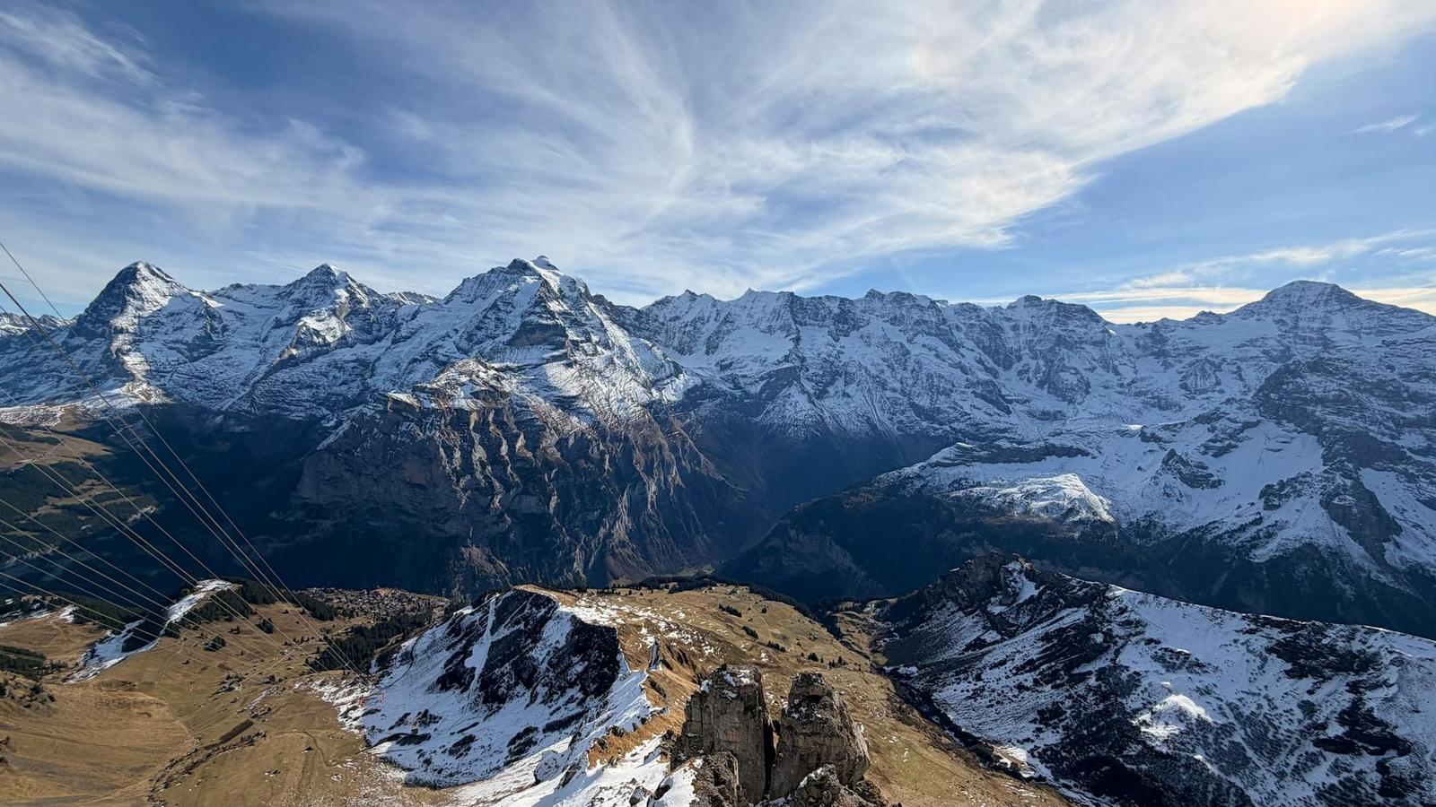 Aerial view of a snow-dusted mountain ridge with cable car lines overhead