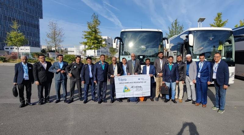Group of people in formal attire posing in front of two large buses