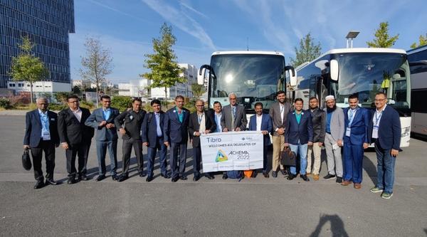 Group of people in formal attire posing in front of two large buses