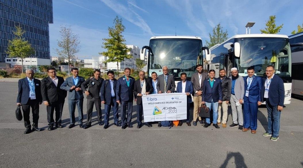 Group of people in formal attire posing in front of two large buses