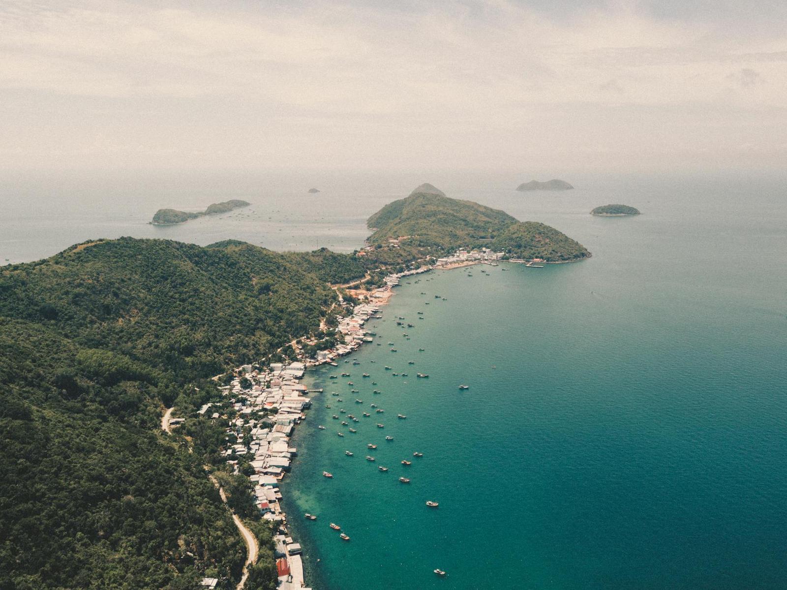 Aerial view of a coastal fishing village on a green headland with boats offshore