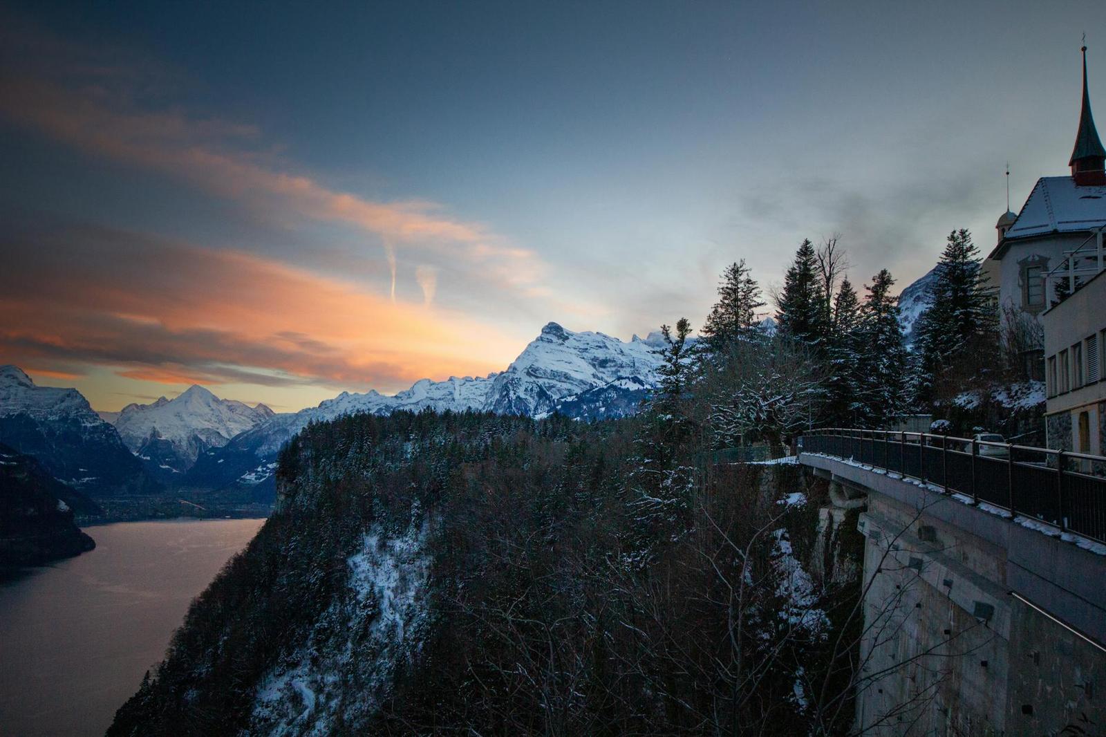 Mountain lake viewpoint at dusk with a stone terrace and pine trees