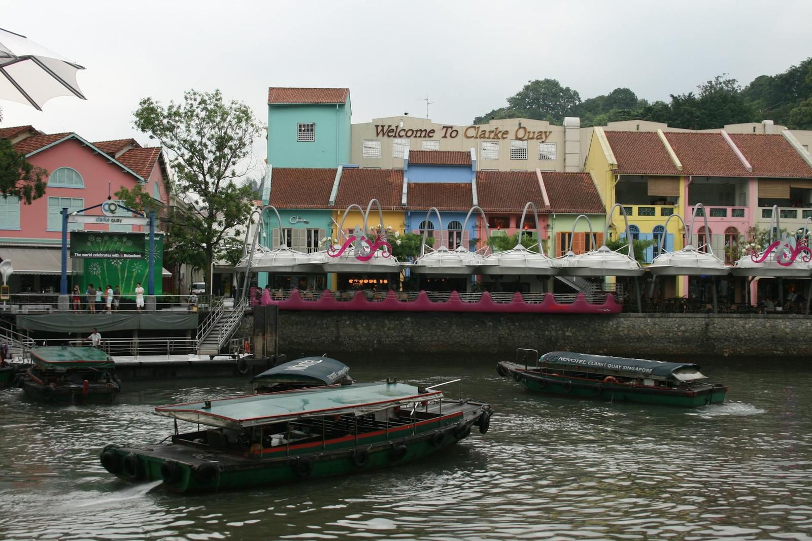 River taxis passing colorful riverside shophouses and restaurants