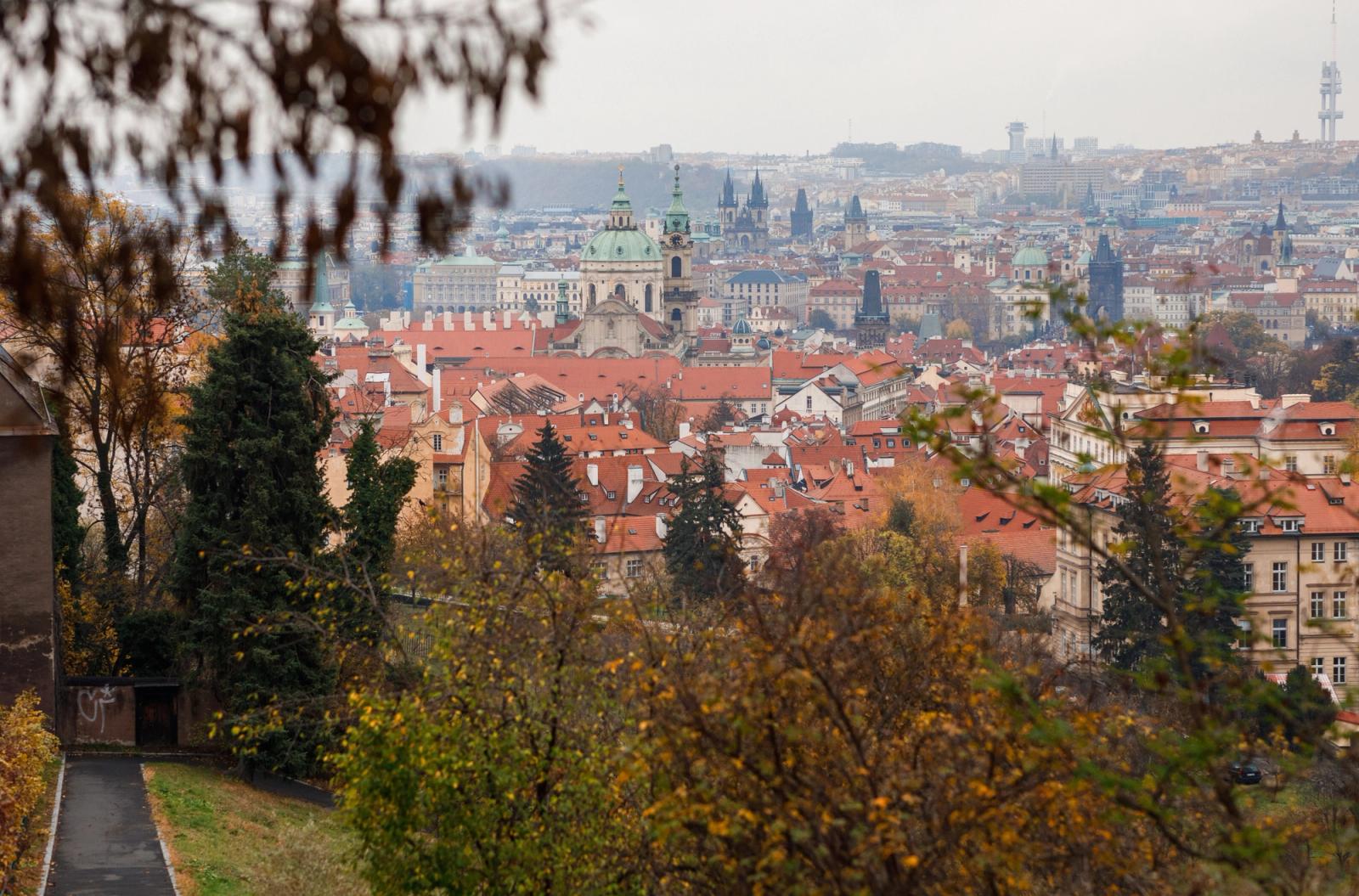 Captivating cityscape of Prague showcasing historic red roofs, churches, and vibrant autumn foliage