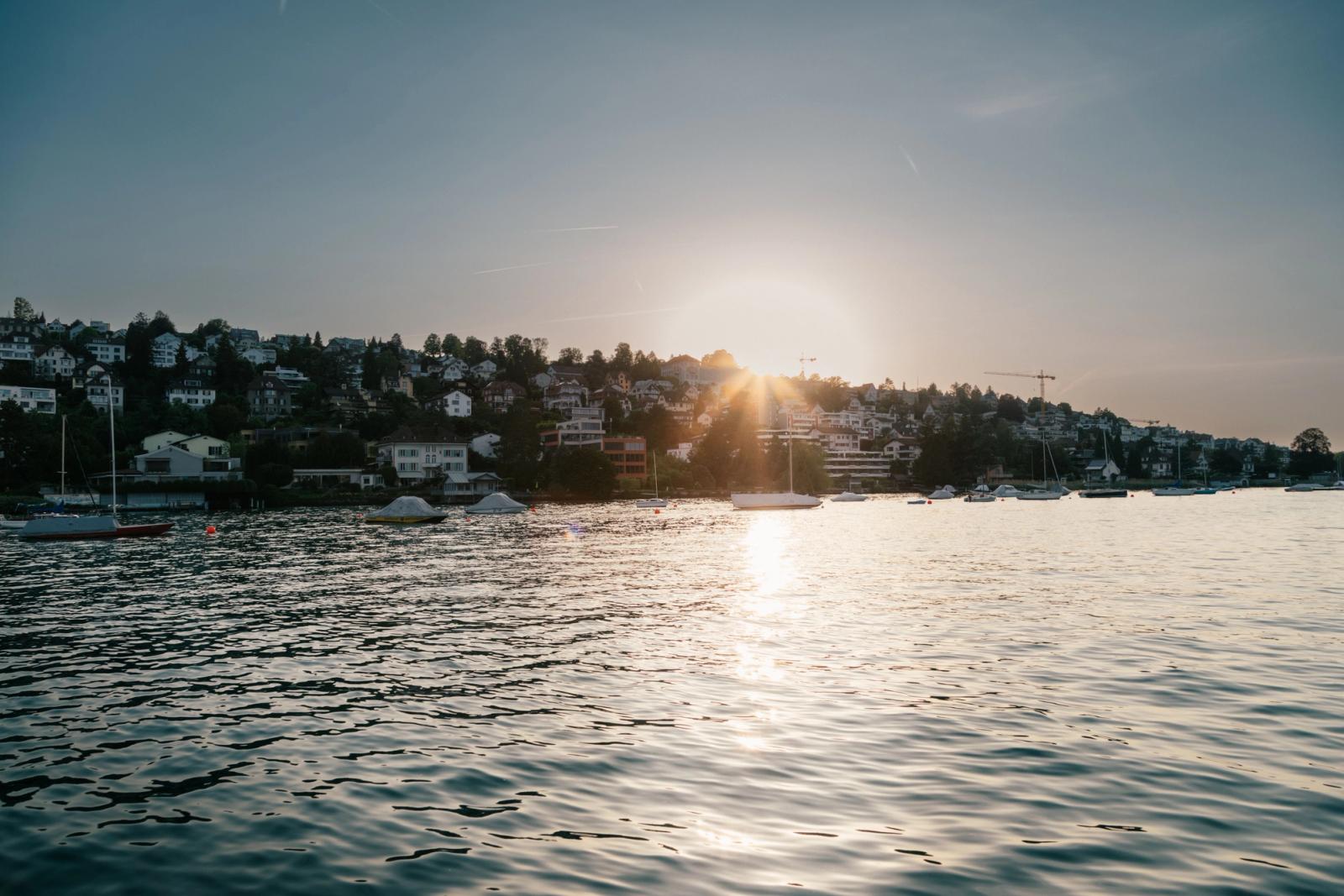 Serene view of Zürich lake at sunset with sailboats and cityscape in the background