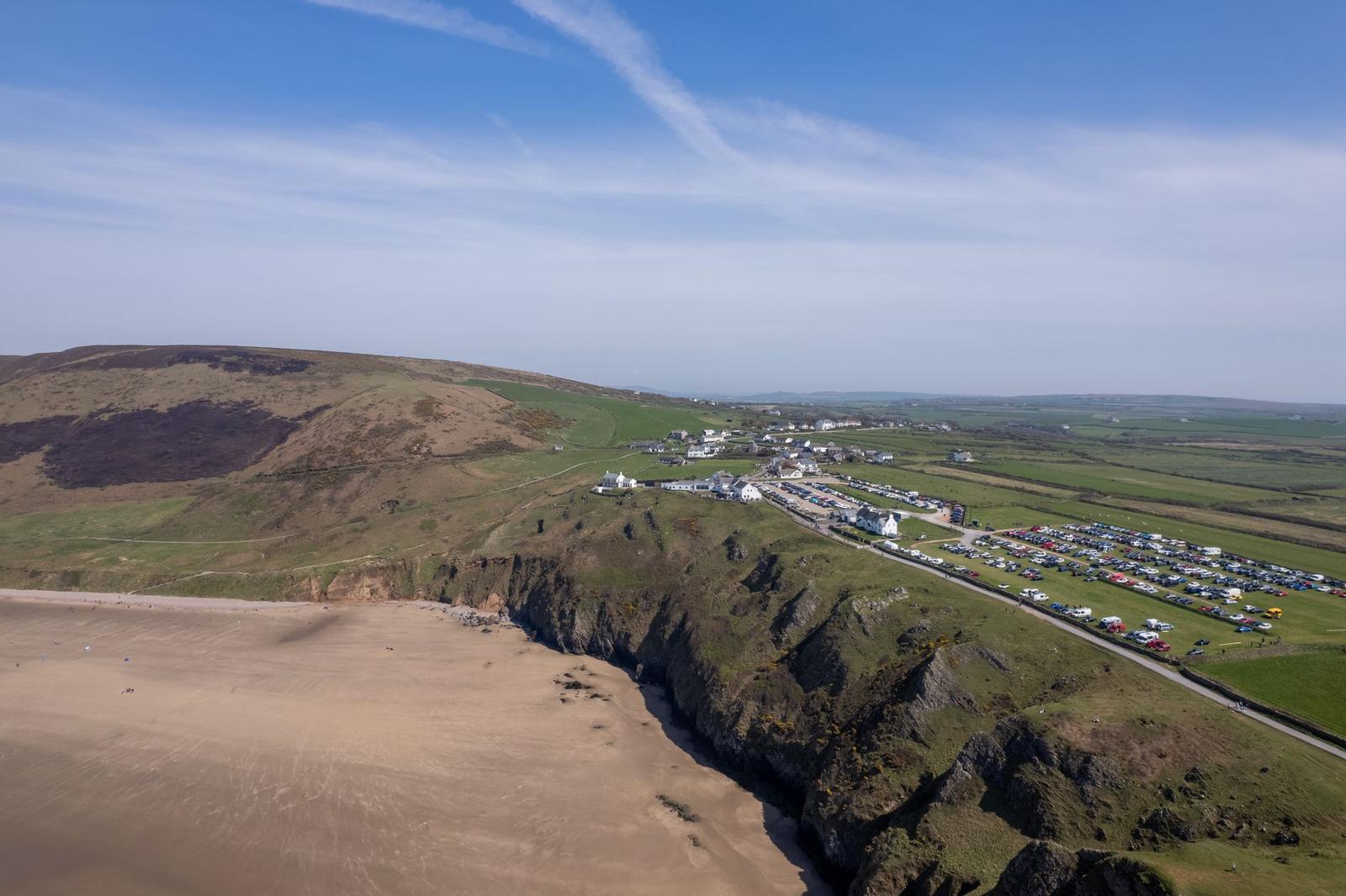 Aerial view of a coastal village on cliffs above a sandy beach